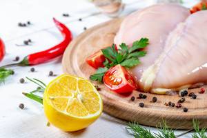 Chicken fillet with spices and herbs, tomatoes and lemon on a wooden Board
