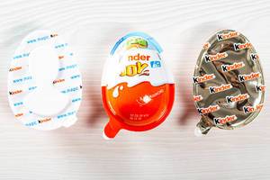 Child kinder joy whole and two halves in packages on the table