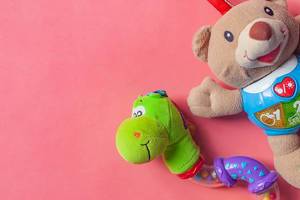 Child rattles. Bear and snake toys for newborn babies on the pink background. View from above. Copy space for text.