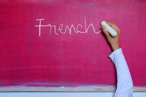 Child writes French word on chalkboard