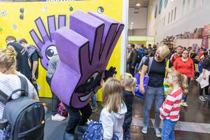 Children meet the purple mascot of card game Dobble at the SPIEL 19 gaming fair in Essen