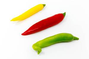 Chilischoten in grün, gelb und rot auf weißem Hintergrund