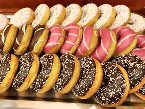 Chocolate and other Donuts with sprinkles laying on a table