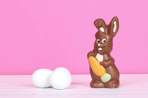 Chocolate bunny with Easter eggs and pink background