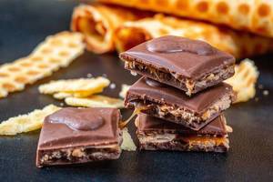 Chocolate cubes with caramel filling and waffles in the background