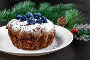 Chocolate cupcake with icing sugar and blueberries on Christmas background