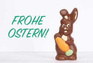 Chocolate easter bunny with Frohe Ostern text on white background