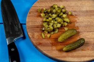 Chopped Pickles on the round wooden board with knife