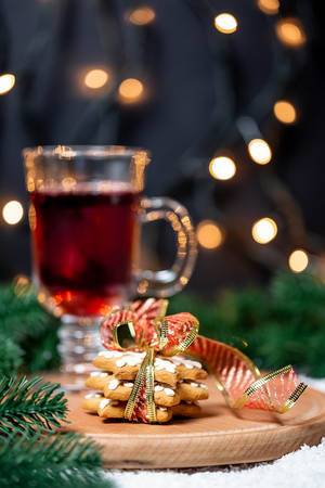 Christmas background with glass of mulled wine, ginger cookies, Christmas tree and garlands