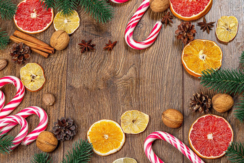 Christmas frame with tree branches, dried fruits, candies and cones on a wooden background (Flip 2019)