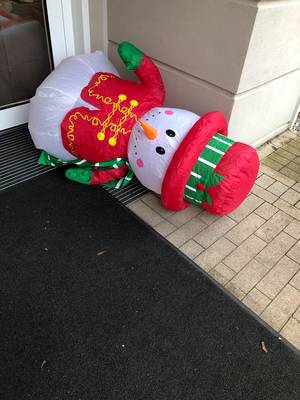 Christmas time is over: Snowman lies on the floor outside the house