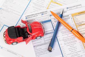 Classic toy car and two pens on accident statement report