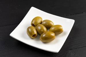 Cleaned Green Olives served on the square plate