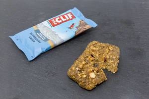 Clif Bar - Energy Bar with Blueberry Crisp Flavor cut in half and Packaging on black plate