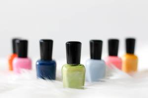 Close Up Bokeh Photo of Nail Polish in different Colors on white Fur on white Background