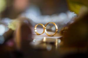 Close Up Bokeh Photo of two Gold Wedding Rings standing on a Wedding Invitation Card