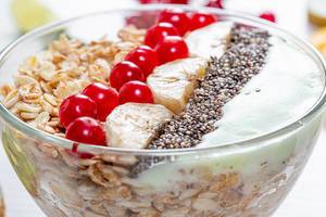 Close-up bowl of oatmeal with Chia seeds, viburnum berries and banana slices