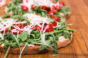 Close Up Food Photo of Bruschetta Fresca with Arugula, Cherry Tomatoes and Parmesan Cheese