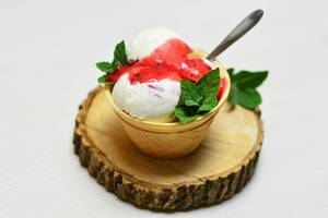 Close Up Food Photo of Ice Cream with Strawberry Fruit Sauce and Mint on a Wooden Plate on White Background