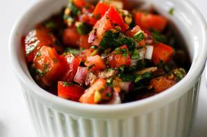 Close Up Food Photo of Mexican Salsa with Tomatoes, Onions and Spices in White Ceramic Cup