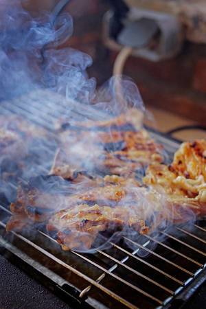 Close Up Food Photo of Pork Meat on a Barbecue Grill with Smoke around it