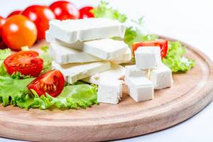 Close Up Food Photo of Stack and Cubes of Feta Cheese, Cherry Tomatoes and Lettuce on Wooden Cutting Board