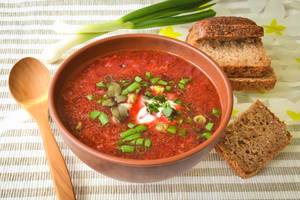 Close Up Food Photo of Ukrainian Sour Soup Borscht with Beetroots, Green Onion and Whole Wheat Bread