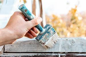 Close up of a brush with white paint in the hand of a man (Flip 2019)