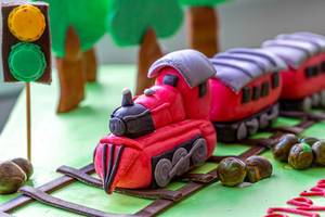 Close-up of a cake decorated with a railway, train and trees made of mastic (Flip 2020)