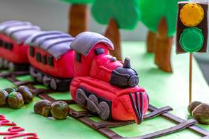 Close-up of a cake decorated with a railway, train and trees made of mastic