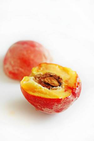 Close-up of a fresh, juicy peach cut in half on white background