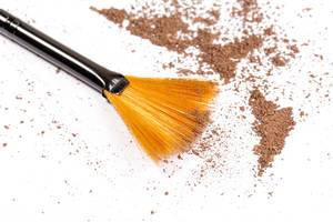 Close-up of a make up powder and a brush on white background
