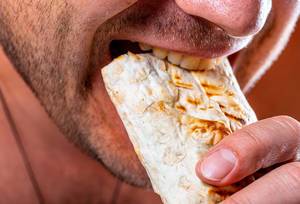 Close-up of a man with bristles biting Shawarma. The concept of fast food (Flip 2019)