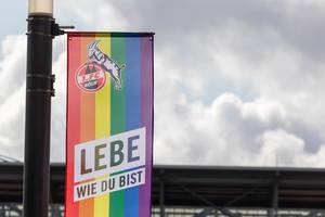Close-up of a rainbow flag of German soccer team 1. FC Köln, with text "live as you are" (lebe wie du bist) for diversity day