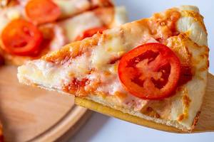 Close-up of a slice of homemade pizza with cheese and tomatoes