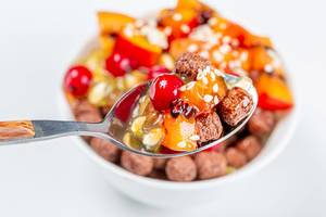 Close-up of a spoon with chocolate corn balls and fruit. The concept of Breakfast