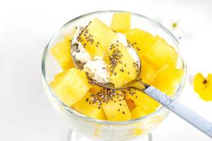 Close- up of a spoon with cottage cheese, pineapple slices and Chia seeds