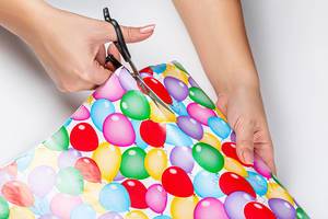 Close-up of a woman cutting gift wrapping paper with scissors
