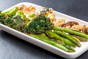 Close-up of asparagus and broccoli with pieces of fish on a white plate
