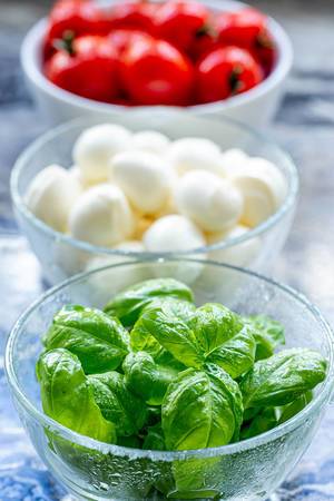 Close-up of Basil leaves and tomatoes with mozzarella behind