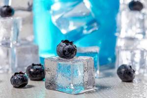 Close-up of blueberries on ice cube with blue cocktail behind (Flip 2019)