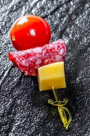 Close-up of canapés with cheese, salami and cherry tomatoes