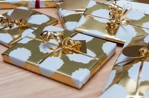 Close Up of Christmas Presents in Golden Gift Wrapping in different Sizes on Wooden Table