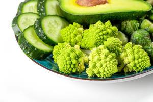 Close-up of fresh slices of romanesco cabbage, cucumber and avocado on a blue plate (Flip 2020)