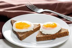 Close-up of fried eggs on pieces of black bread