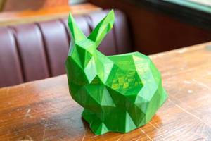 Close-up of green rabbit printed by a 3D printer on a wooden table