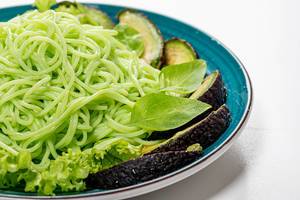 Close up of green spaghetti with avocado slices and basil (Flip 2019)