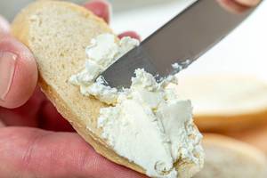 Close-up of hand spread cheese on bread with a knife (Flip 2019)