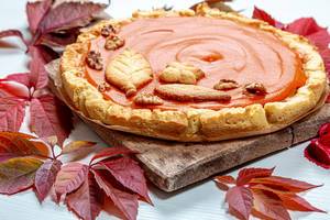 Close - up of homemade pumpkin pie on an old kitchen Board with colorful autumn leaves. The concept of the autumn holidays