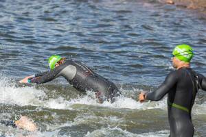 Close-up of Ironman swimmers jumping heads first into a lake for the first triathlon discipline and create water splashes